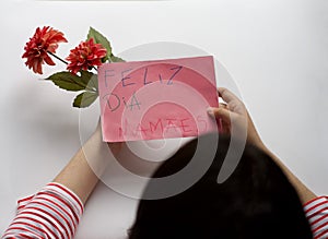 Mother holding flowers and handmade greeting card. Message in Portuguese Ã¢â¬ÅFeliz Dia MamÃÂ£esÃ¢â¬Â photo